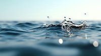 Dynamic water surface with droplets splashing and creating ripples against blurred aqua background, captured in macro photography with soft natural lighting.