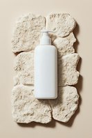 White pump bottle with dispenser on textured stone platform against neutral background, suitable for skincare, cosmetics, beauty product packaging mockups and branding designs.