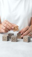 Woman hands selecting happy face wooden cube from sad emotion blocks representing positive mindset choice and mental health wellness concept.