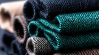 Neatly folded stack of clean cotton towels in turquoise and charcoal gray colors showing detailed fabric texture and layers, suitable for spa and bathroom decor.
