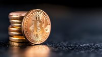 Stack of golden cryptocurrency coins with bitcoin on dark textured surface, dramatic lighting highlights digital currency investment concept.
