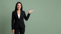 Professional businesswoman in black suit presenting with open hand gesture on green background for corporate marketing materials.