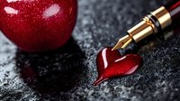 Red heart drawn with fountain pen ink next to shiny red apple on dark textured background, romantic writing and education concept for valentines day cards and love letters.