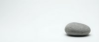 Single smooth gray stone on clean white background for zen meditation spa wellness design projects.