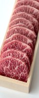 Sliced premium marbled wagyu beef arranged in wooden box showing distinctive meat texture and rich fat marbling pattern. Close up view on white background.