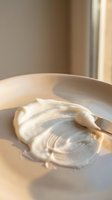 Luxurious cream texture swirl in ceramic bowl with warm natural lighting for skincare and beauty product concepts.