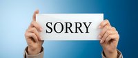 Caucasian person holding a white card with the word SORRY on blue background, expressing apology, regret, and sincere forgiveness in business concept.