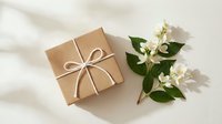 Kraft paper gift box tied with twine bow beside white jasmine flowers on light background with soft shadows.