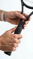 Close-up of mature male hands gripping tennis racket handle against white background. Sports equipment detail for athletic training and recreation concepts.