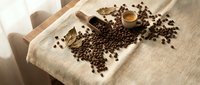Coffee beans scattered on linen fabric with wooden scoop and small bowl creating rustic kitchen scene for culinary and beverage themed designs.