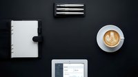 Modern workspace flat lay with tablet, notebook, coffee cup and pens on dark background for business productivity and planning concepts.