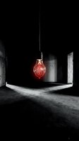 Glowing red light bulb with dollar sign hanging in dark concrete room symbolizing business ideas and financial innovation concepts.