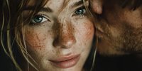 Young blonde woman with freckles and green eyes in warm sunlight creating natural shadows on face for beauty and skincare concepts.
