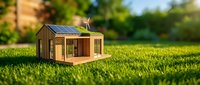 Miniature eco-friendly house model with solar panels on green grass lawn showcasing sustainable living and renewable energy concepts for environmental design.