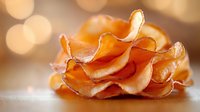 Crispy bacon strips arranged in decorative rose-like formation on wooden surface with warm golden bokeh lights creating cozy breakfast atmosphere.