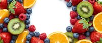 Fresh mixed berries and citrus fruits arranged in circular frame on white background creating colorful border for healthy eating and nutrition concepts.