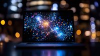 Glowing cosmic explosion displayed on laptop screen with blurred bokeh lights in background, creating magical atmosphere for space and technology concepts.