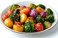 Colorful roasted vegetables with broccoli florets, cherry tomatoes, and red onions garnished with sesame seeds and herbs served on white plate, healthy side dish.