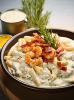 Creamy pasta with shrimp, crispy bacon and fresh dill in rich white sauce, garnished with rosemary sprig, served in brown ceramic bowl. Comfort food styling.