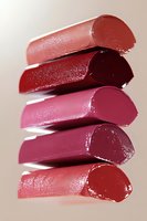 Stacked cross-sections of lipsticks in various shades of pink and red showing texture and color depth against neutral background, highlighting cosmetic product detail.