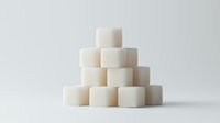White sugar cubes stacked in pyramid formation on light background, minimalist composition showing geometric shapes and patterns in food photography.
