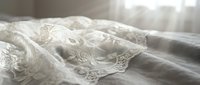 Delicate ivory lace fabric with ornate floral embroidery details draped softly on neutral background, suitable for wedding, bridal, and textile design projects.