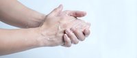 Senior man massaging painful arthritic hands showing joint inflammation and stiffness on white background for medical healthcare concepts.