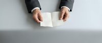 Business professional hands holding blank white envelope on clean desk surface for corporate communication and correspondence needs.