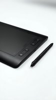 Black graphics tablet with stylus pen on white background, isolated for design, digital art, and creative work applications.