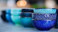 Handcrafted ceramic bowls in shades of blue and turquoise with intricate geometric patterns, arranged in row showing traditional pottery craftsmanship.