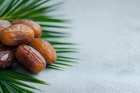 Fresh dates with palm leaves on textured surface for healthy eating and Middle Eastern cuisine concepts.