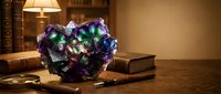 Mystical glowing crystal cluster with purple and green luminescence on vintage wooden desk surrounded by antique books in warm library setting.