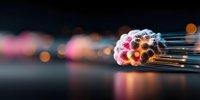 Colorful fiber optic cables bundled together with glowing ends against dark background, creating abstract technology concept with bokeh light effect.