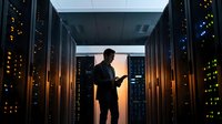 IT professional managing server infrastructure in modern data center with glowing equipment racks and network systems for technology operations.