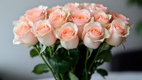 Fresh peach-colored roses in full bloom arranged in elegant bouquet with green stems and leaves against soft blurred background, romantic floral composition.