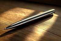 Elegant metallic pen lying on wooden surface in dramatic lighting with golden sunbeam highlighting luxurious business accessory for professional settings.