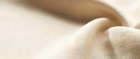 Soft beige fabric with gentle folds and smooth texture creating elegant drapery for fashion design, interior decoration and textile backgrounds.