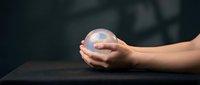 Hands gently holding glowing sphere with digital interface elements. Futuristic technology concept for innovation, artificial intelligence and digital transformation.