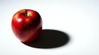 Fresh red apple with glossy skin casting shadow on white background. Healthy organic fruit for nutrition, diet and wellness concepts.