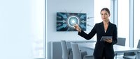 Professional businesswoman presenting digital technology interface in modern conference room with tablet device for corporate meetings and presentations.