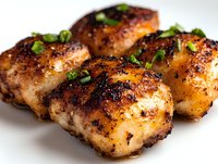 Juicy grilled chicken thighs with crispy spiced skin and fresh herbs garnish on white background, close-up view of succulent meat for food photography and menu design.
