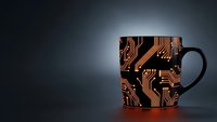 Black coffee mug with copper circuit board pattern design on dark background for technology and electronics themed projects.