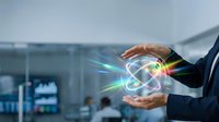 Businessman hands protecting glowing atomic symbol with energy beams in modern office environment representing nuclear technology and scientific innovation.