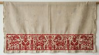 Linen fabric with traditional red embroidered border featuring ornamental animals and scrollwork patterns, suitable for home decor and textile design projects.