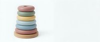 Stacked pastel silicone rings in pink, green, yellow, blue and natural wood tones on white background for baby development and sensory play.