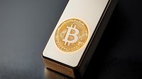 Golden cryptocurrency coin on modern smartphone against dark background, minimalist composition highlighting digital finance and mobile trading concept.