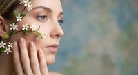 Young Caucasian woman with natural makeup touching face with delicate white flowers, skincare and beauty concept for spa treatments and cosmetics.