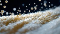 Macro photography of water droplets on soft beige textured surface with bokeh effect and shallow depth of field creating dreamy atmospheric composition.