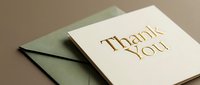 Elegant thank you card with gold foil lettering beside a dark green envelope on a warm beige background, perfect for gratitude and celebration.
