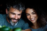 Happy mature man with gray curly hair and beard embracing smiling young woman with curly brown hair in cozy indoor setting for lifestyle content.